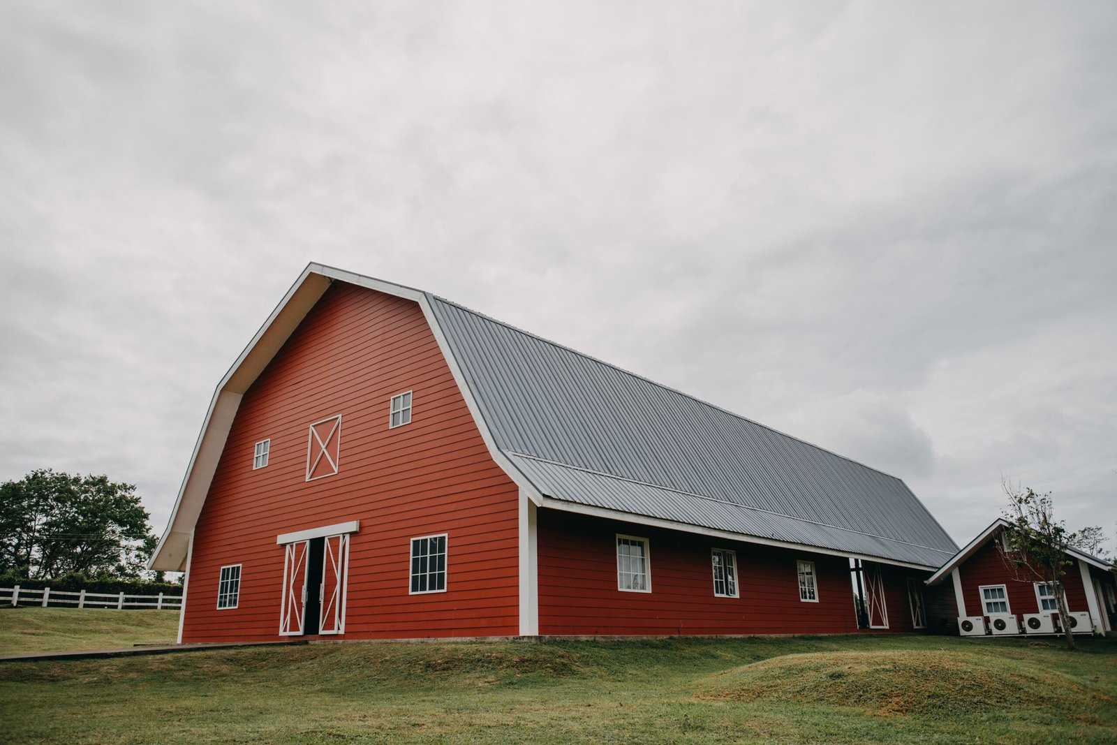 Red barn in the rolling countryside of the Philippines under a cloudy sky.